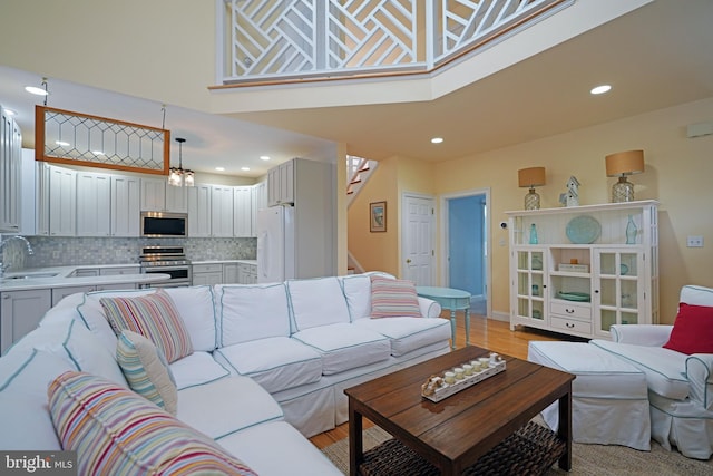 living room with sink, light hardwood / wood-style flooring, and a high ceiling