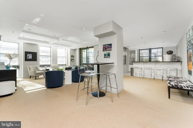 kitchen with coffered ceiling, light colored carpet, beam ceiling, and a breakfast bar area