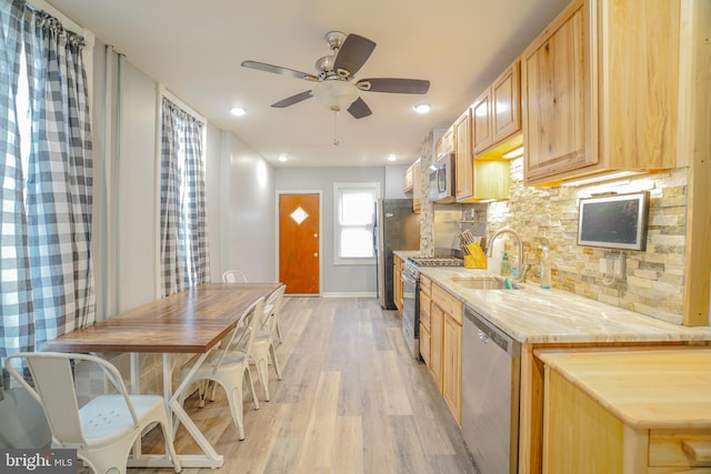 kitchen featuring backsplash, sink, light hardwood / wood-style flooring, appliances with stainless steel finishes, and light brown cabinetry