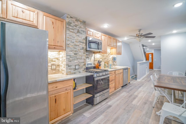 kitchen with light wood-type flooring, appliances with stainless steel finishes, light brown cabinetry, and backsplash