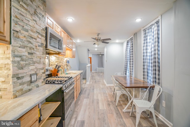 kitchen featuring stainless steel appliances, decorative backsplash, light brown cabinetry, light wood-type flooring, and ceiling fan