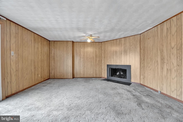 unfurnished living room with light carpet, ceiling fan, wooden walls, and a textured ceiling