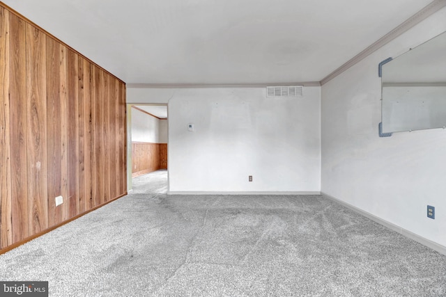 carpeted spare room with ornamental molding and wood walls