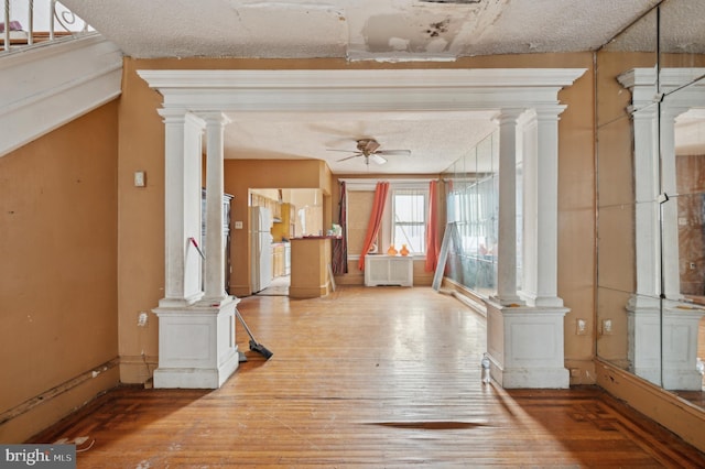 entryway featuring ceiling fan, wood-type flooring, a textured ceiling, and ornate columns