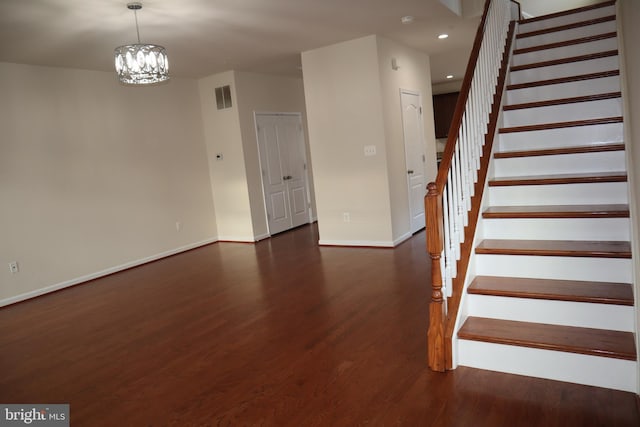 stairway with hardwood / wood-style floors and a notable chandelier