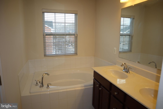 bathroom with vanity and tiled tub