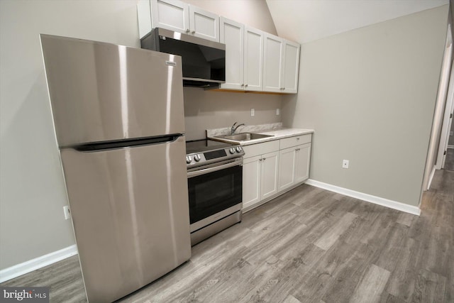 kitchen with vaulted ceiling, appliances with stainless steel finishes, sink, and white cabinets