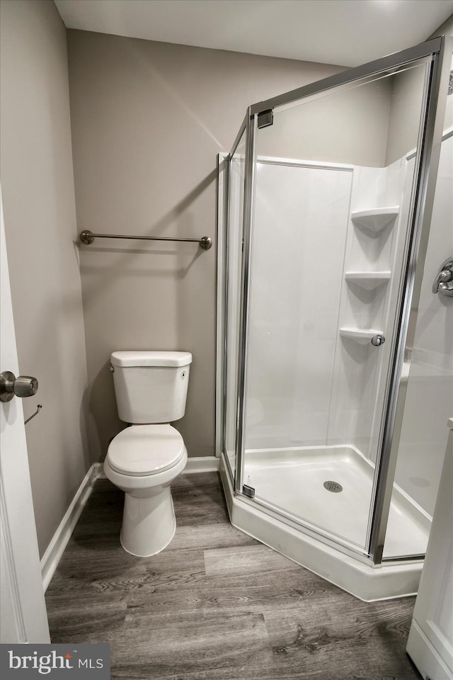 bathroom featuring toilet, hardwood / wood-style floors, and a shower with shower door