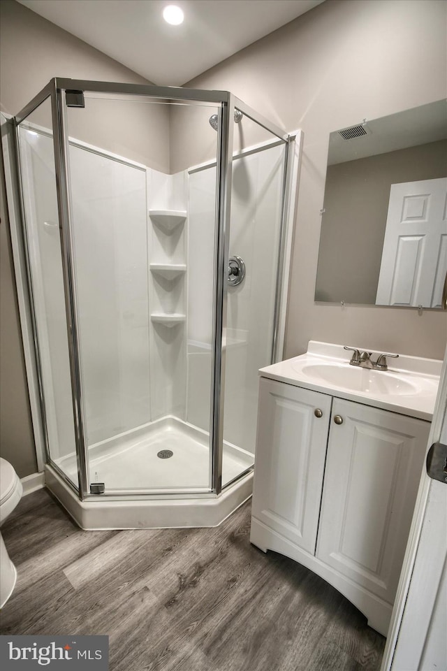 bathroom with vanity, hardwood / wood-style flooring, a shower with shower door, and toilet