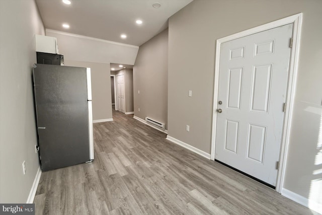 kitchen featuring stainless steel refrigerator, lofted ceiling, light hardwood / wood-style flooring, and a baseboard heating unit