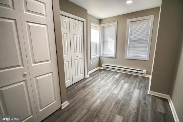 unfurnished bedroom with dark wood-type flooring and a baseboard heating unit