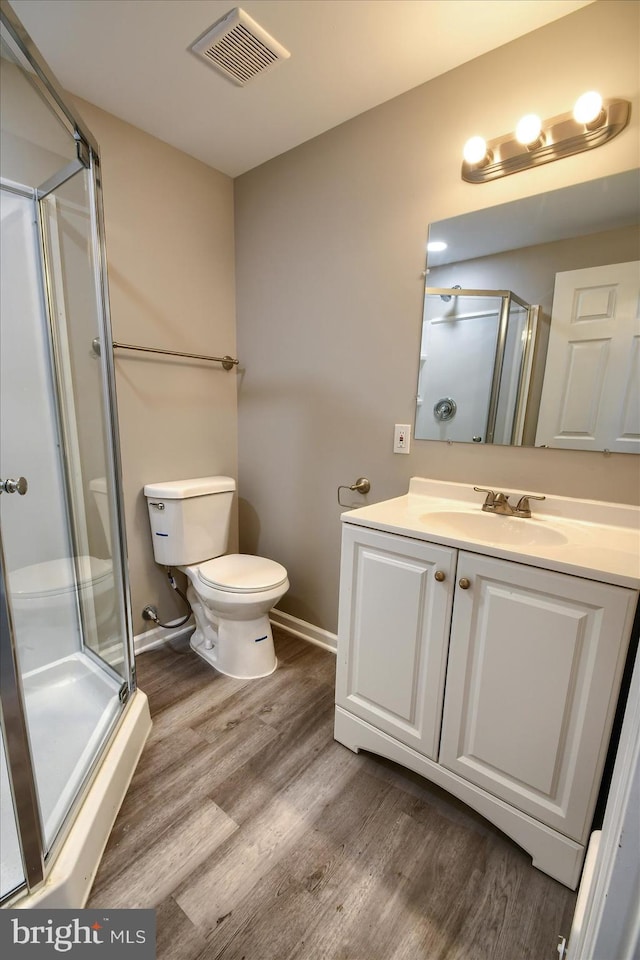 bathroom with vanity, hardwood / wood-style floors, a shower with shower door, and toilet