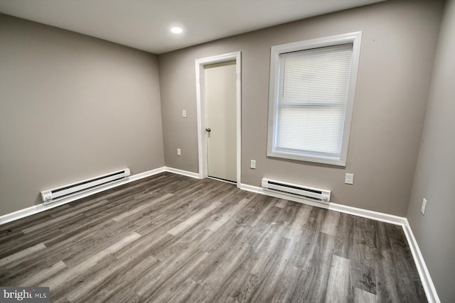 empty room featuring dark wood-type flooring and a baseboard heating unit