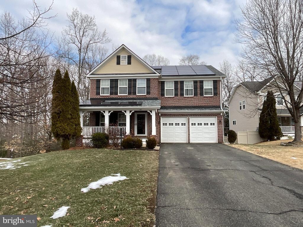 view of front facade with a garage, a front lawn, covered porch, and solar panels