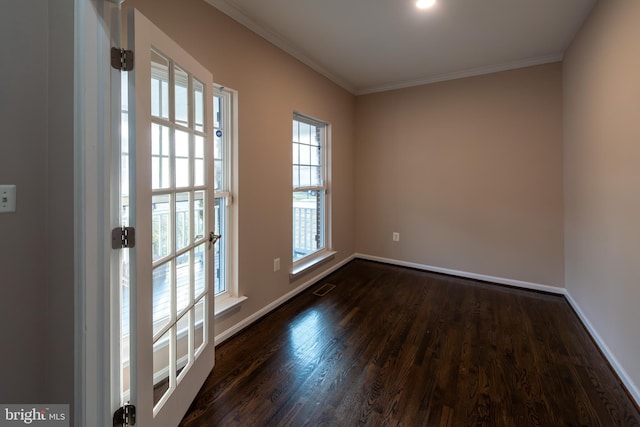 spare room featuring a healthy amount of sunlight, dark hardwood / wood-style floors, and ornamental molding