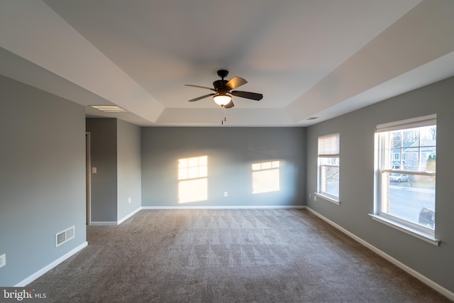 carpeted empty room with a tray ceiling and ceiling fan