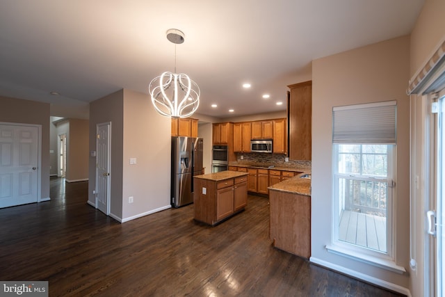 kitchen featuring hanging light fixtures, backsplash, stainless steel appliances, light stone countertops, and a kitchen island