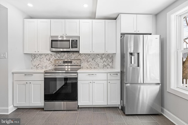 kitchen featuring appliances with stainless steel finishes, white cabinets, and decorative backsplash