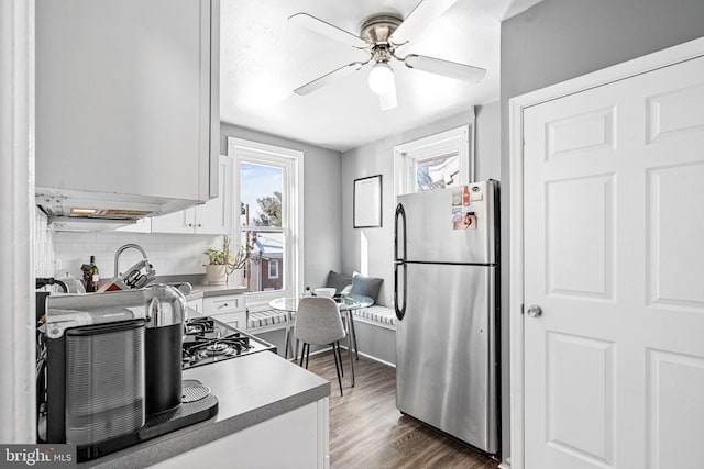 kitchen featuring dark hardwood / wood-style floors, stainless steel fridge, ceiling fan, decorative backsplash, and white cabinets