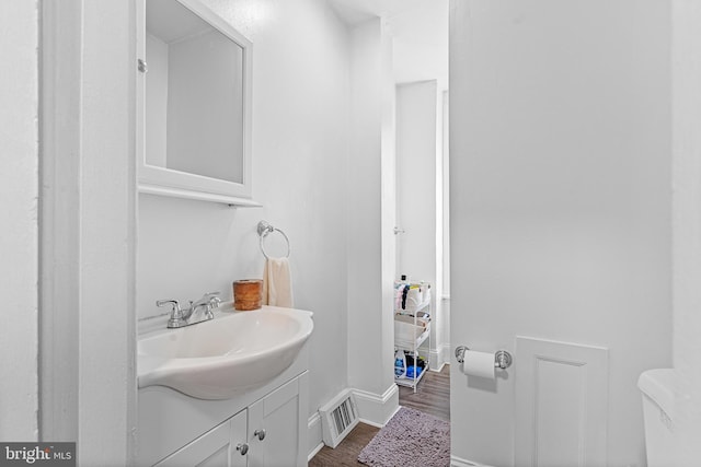 bathroom with wood-type flooring, toilet, and vanity