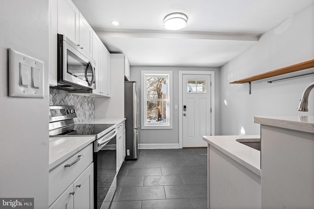 kitchen with white cabinetry, backsplash, stainless steel appliances, and light stone countertops