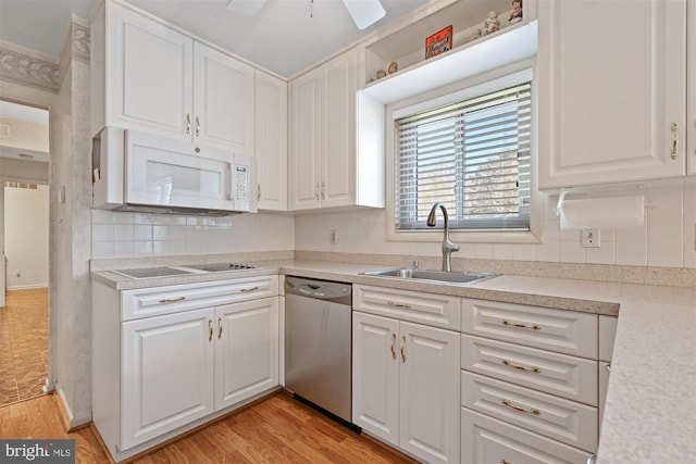 kitchen featuring white cabinets, dishwasher, white microwave, light countertops, and a sink