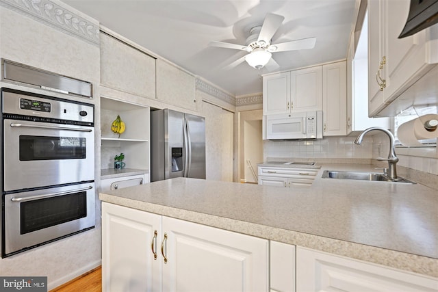 kitchen with appliances with stainless steel finishes, white cabinets, light countertops, and a sink