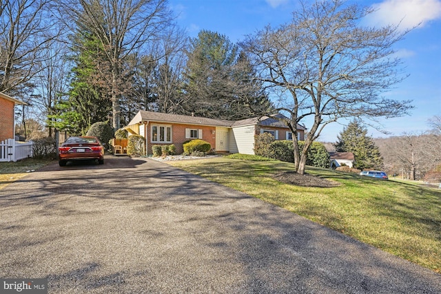 view of front of property featuring aphalt driveway, fence, a front lawn, and brick siding