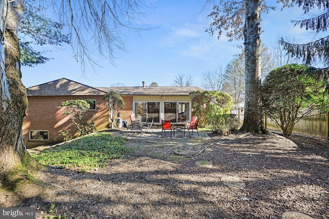 back of property with brick siding, a patio, and fence