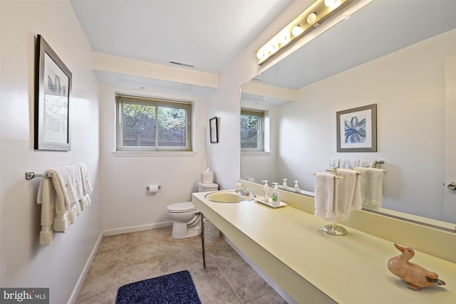 bathroom featuring toilet, a sink, visible vents, baseboards, and tile patterned floors