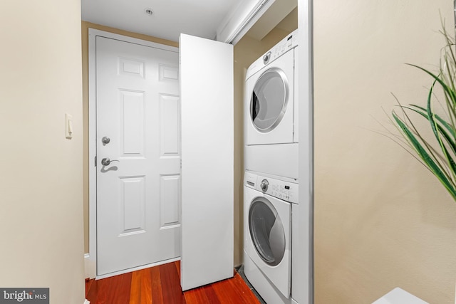 laundry area featuring dark wood-type flooring and stacked washer / drying machine