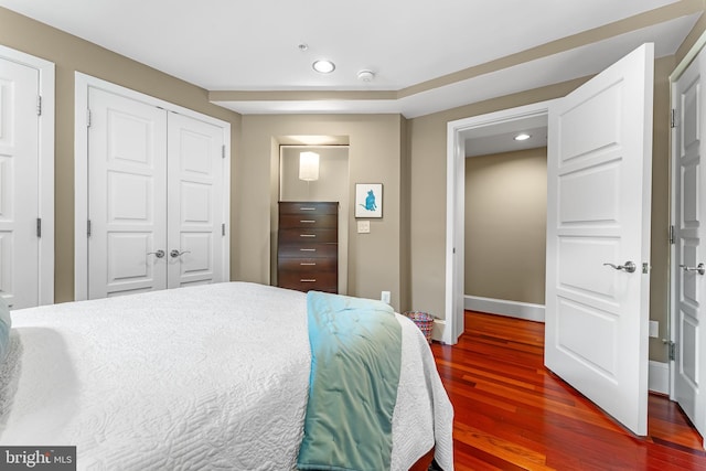 bedroom with dark wood-type flooring and a closet