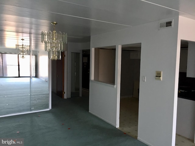 carpeted empty room with an inviting chandelier