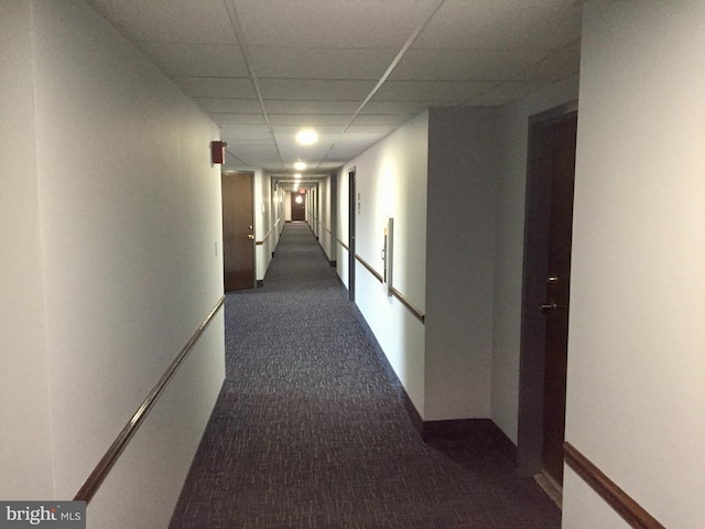 corridor with dark carpet and a drop ceiling