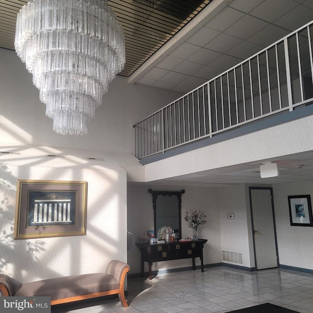 staircase with tile patterned floors, a towering ceiling, and an inviting chandelier