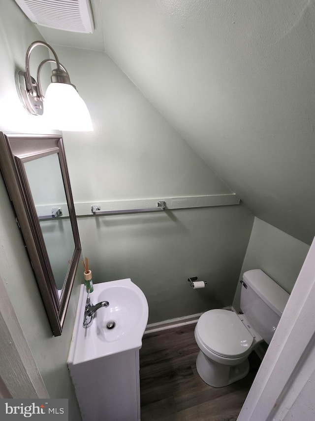 bathroom featuring lofted ceiling, vanity, wood-type flooring, and toilet