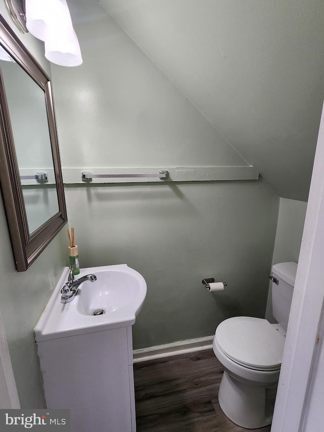 bathroom featuring vanity, hardwood / wood-style flooring, vaulted ceiling, and toilet