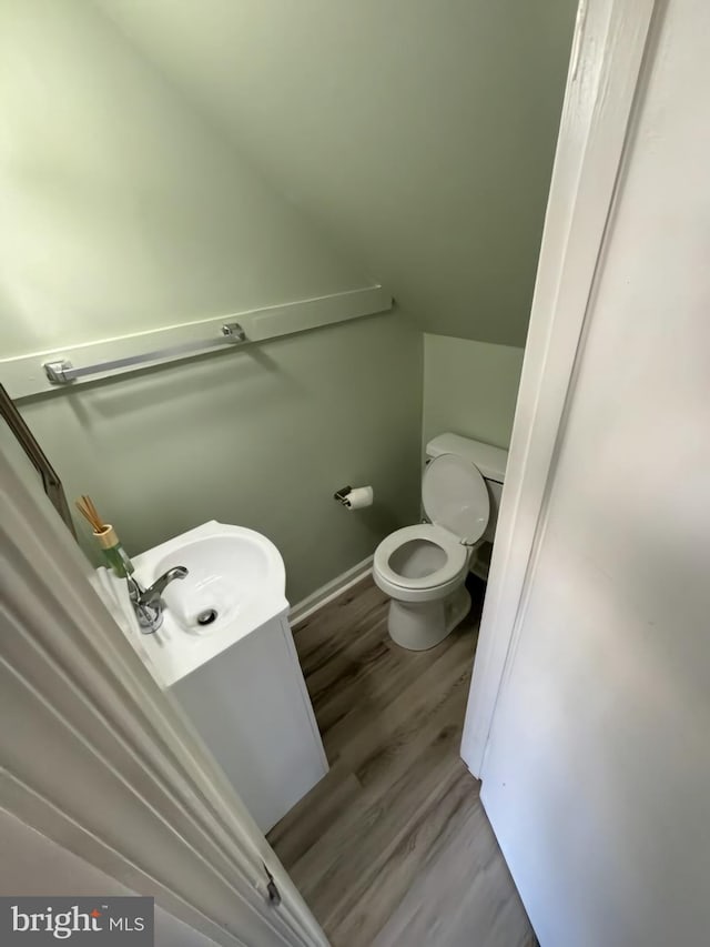 bathroom featuring vaulted ceiling, wood-type flooring, toilet, and sink