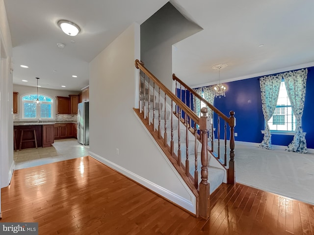 stairway featuring sink, hardwood / wood-style floors, and an inviting chandelier