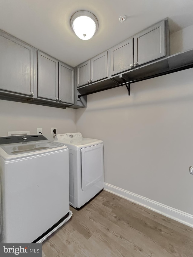 clothes washing area featuring light wood-type flooring, cabinets, and independent washer and dryer