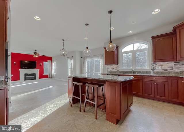 kitchen with light stone counters, sink, a center island, and tasteful backsplash