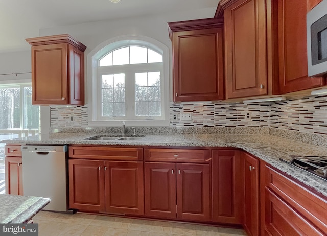 kitchen with light stone countertops, sink, backsplash, and stainless steel appliances