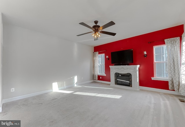 unfurnished living room with ceiling fan, light colored carpet, and a premium fireplace