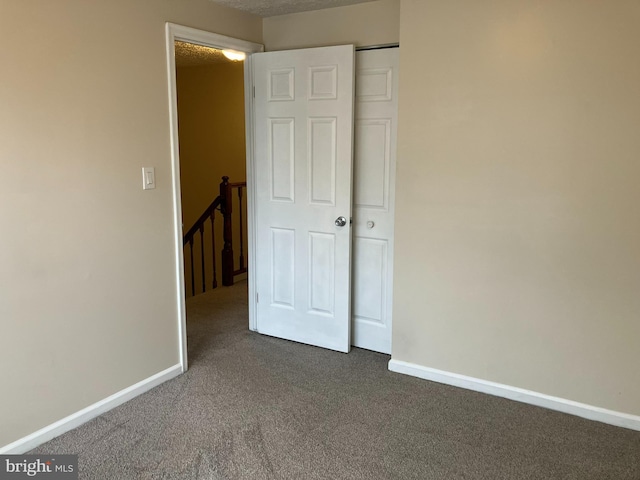 unfurnished bedroom with dark colored carpet and a closet