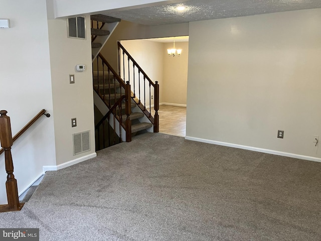 interior space featuring a textured ceiling, carpet floors, and a notable chandelier