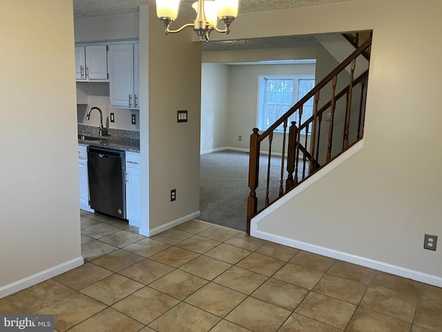 kitchen featuring white cabinets, stainless steel dishwasher, an inviting chandelier, sink, and light tile patterned floors