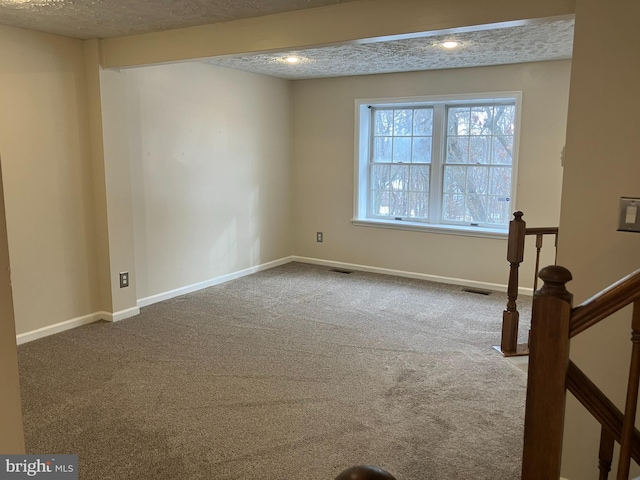 carpeted empty room featuring a textured ceiling