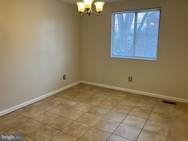 tiled spare room with an inviting chandelier