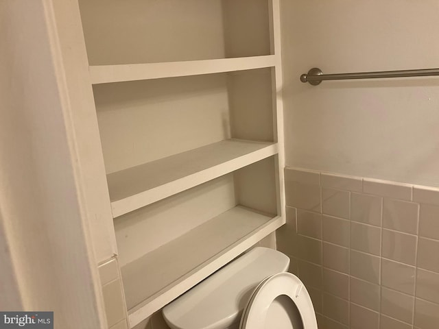 bathroom with toilet and tile walls