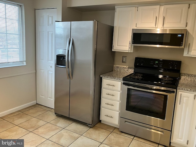 kitchen featuring light stone countertops, white cabinets, appliances with stainless steel finishes, and light tile patterned floors